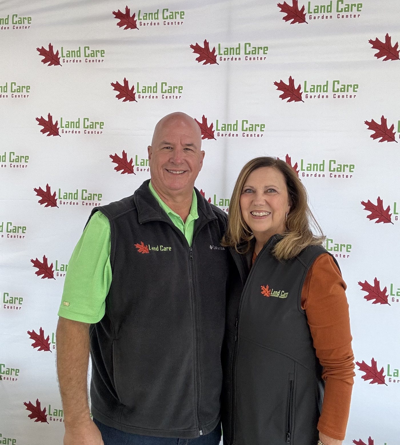 Steve and Karen Cammack, owners of Land Care Garden Center, in front of the Land Care Garden Center backdrop