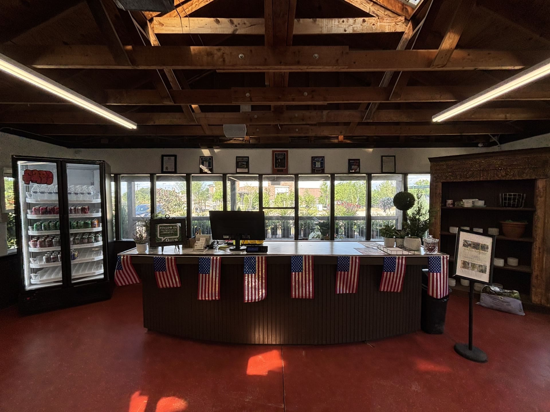 Inside Land Care Garden Center: the checkout counter with its beverage cooler and awards wall under the open beam ceiling