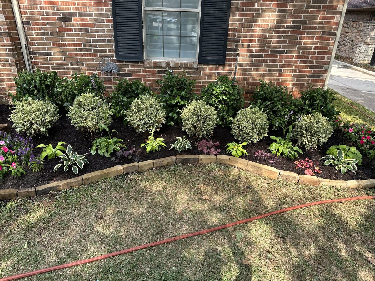A finished front garden bed installation by Land Care Landscape Management, with stone edging and fresh planting