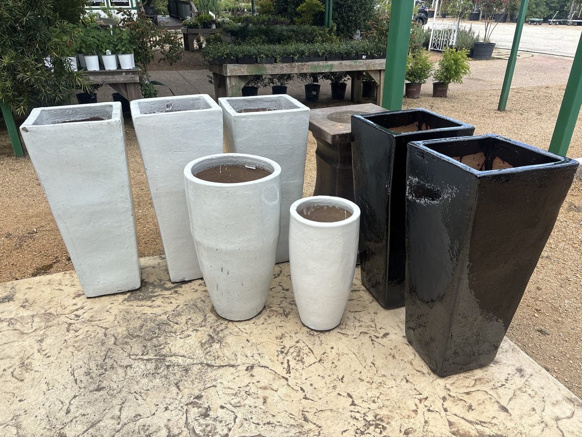 Tall white, cream, and black pottery grouped by color and size on the display pad at Land Care Garden Center